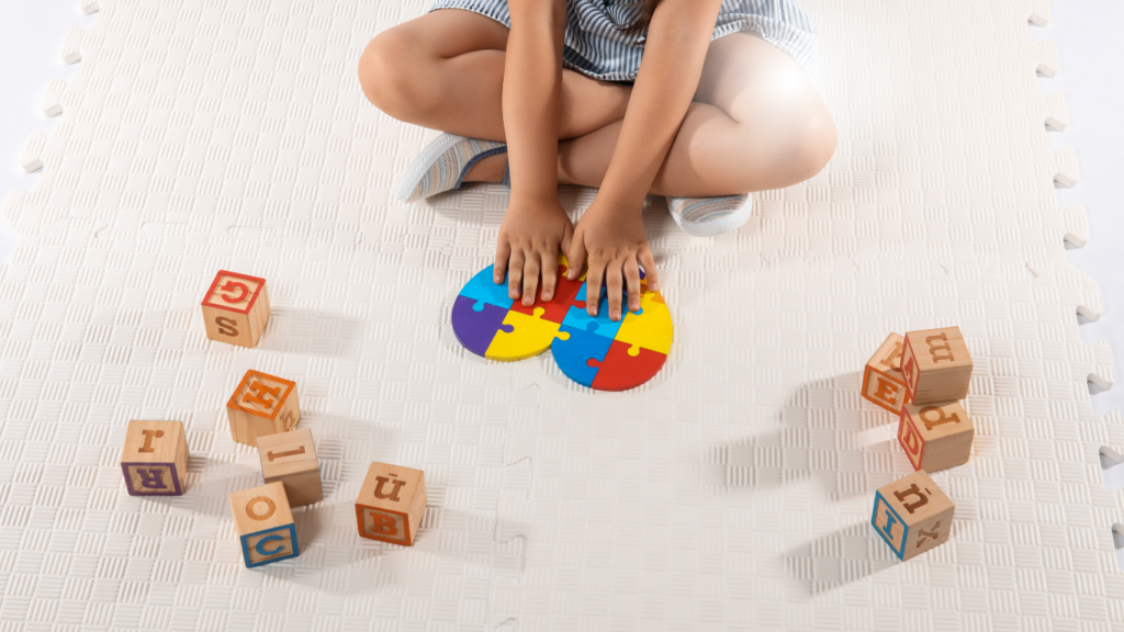Criança sentada no chão montando quebra-cabeça colorido, ilustrando o direito de crianças com autismo à cobertura de Terapia ABA pelo plano de saúde.