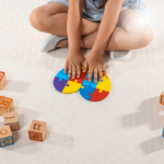 Criança sentada no chão montando quebra-cabeça colorido, ilustrando o direito de crianças com autismo à cobertura de Terapia ABA pelo plano de saúde.